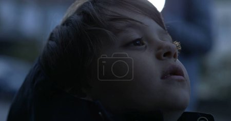 Foto de Cara de primer plano del niño pensativo reflexivo mirando hacia arriba con expresión en blanco en la hora del atardecer por la tarde - Imagen libre de derechos
