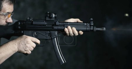 Photo for High-Speed Shooting with HK SP5K Assault Rifle, Side Perspective of Person Aiming and Firing - Royalty Free Image