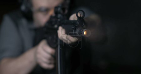 Photo for Close-up of man aiming and firing an assault rifle in slow-motion, captured at high-speed 800 fps. Person shooting powerful weapon - Royalty Free Image