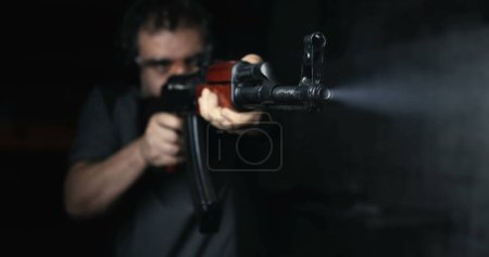 Mann zielt mit Kalaschnikow-Waffe in Super-Zeitlupe mit hoher Geschwindigkeit 800 fps, Vorderansicht AK-47 Gewehr