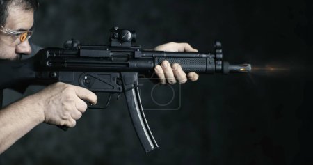 Foto de Disparos de alta velocidad con fusil de asalto HK SP5K, perspectiva lateral de la persona apuntando y disparando - Imagen libre de derechos