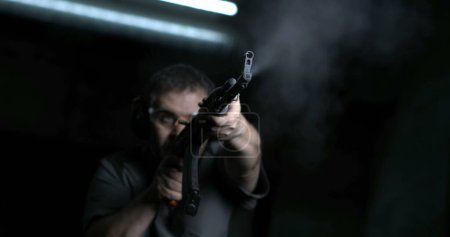 Photo for Man aiming and firing with weapon in super slow-motion 800 fps. Person holding an AK-47 Kalashnikov Rifle, low-angle perspective - Royalty Free Image