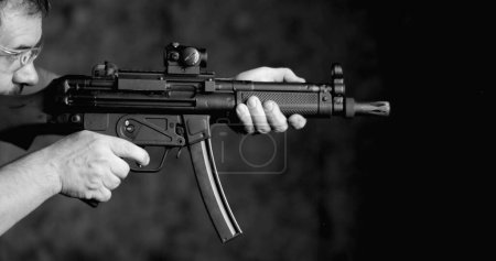 Téléchargez les photos : Vue latérale de la personne qui vise et tire HK SP5K, tir au fusil d'assaut allemand à grande vitesse, en noir et blanc monochromatique - en image libre de droit