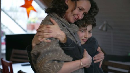 Photo for Mother and pre-teen small boy son embrace in authentic real life loving affectionate scene, family lifestyle, child with arm around mom - Royalty Free Image