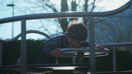 Foto de Niño jugando alegremente en carrusel en el patio de recreo girando de una manera despreocupada, niño pequeño disfrutando deliciosamente en la rotonda del parque - Imagen libre de derechos