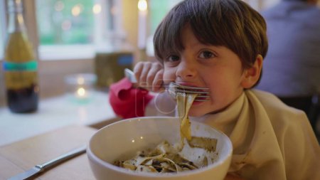 Photo for Child eating past spaghetti on bowl. Hungry small boy enjoying meal food at restaurant - Royalty Free Image