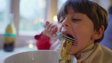 Photo for Close-up child enjoying spaghetti pasta on bowl, little boy eating Italian food at restaurant with napkin on collar - Royalty Free Image