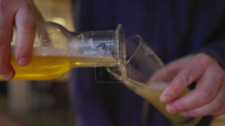 Téléchargez les photos : Servir de la bière dans une tasse en verre. Gros plan serveur versant boisson alcoolisée pour le client - en image libre de droit