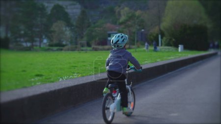 Foto de Niño enérgico montando en bicicleta al aire libre en el parque, niño con paseos en casco protector bicicleta - Imagen libre de derechos