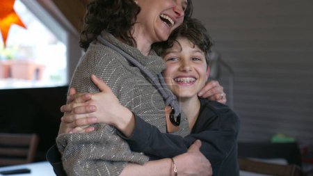 Photo for Candid mother and pre-teen boy laughing together. Authentic moment of family lifestyle joy with child with arm around mom in affectionate embrace - Royalty Free Image
