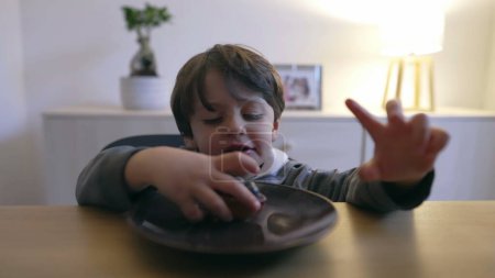 Téléchargez les photos : Petit garçon attrapant collation gâteau aux myrtilles de l'assiette. Enfant mangeant du sucre mais des aliments sains dessert indulgence - en image libre de droit