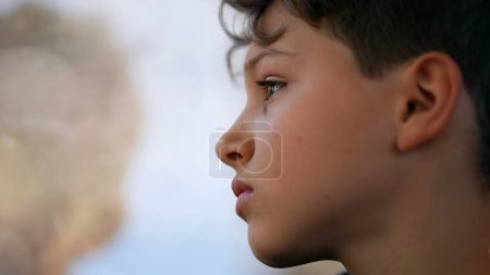 Photo for Thoughtful young boy gazing at train window looking at landscape pass by while traveling, profile close-up face of pre-teen child in transportation - Royalty Free Image