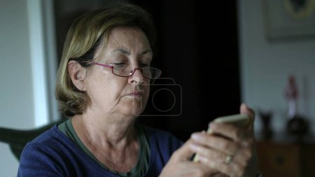 Téléchargez les photos : Femme âgée avec des lunettes axées sur le contenu Smartphone - en image libre de droit
