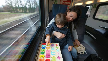 Photo for Devoted mother and her child engaging in a school-related task aboard a high-speed train, utilizing travel time productively - Royalty Free Image