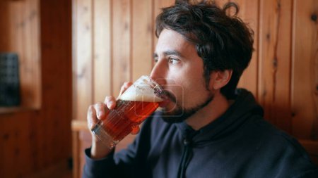 Téléchargez les photos : Homme buvant de la bière pression dans un restaurant en bois - en image libre de droit
