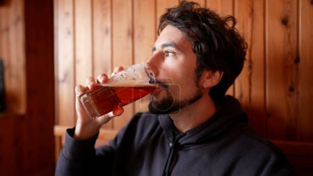 Téléchargez les photos : Savourer la bière - Homme appréciant la bière brouillon dans la bouffe en bois rustique - en image libre de droit