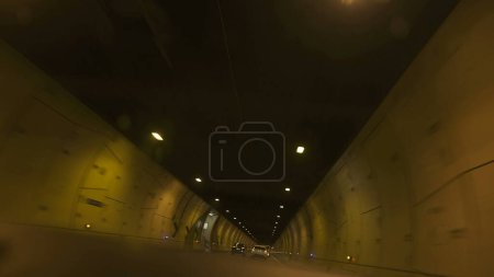 Téléchargez les photos : Conduite à l'intérieur du tunnel avec des lumières brillantes au plafond, concept de transport rapide - en image libre de droit