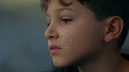 Photo for Pensive introspective child close-up face traveling by train stares at window looking at scenery pass by with a contemplative emotion - Royalty Free Image
