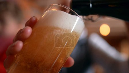 Photo for Filling Glass with Beer at Restaurant, traditional golden pour, close-up face holding refreshing drink - Royalty Free Image