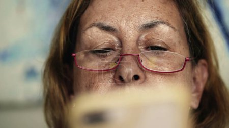 Foto de La mirada de ancianos - Mujer mayor lee contenido en línea a través del teléfono celular, lector digital, primer plano de la señora mayor navegando en el móvil con gafas - Imagen libre de derechos