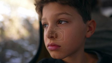 Photo for Child feeling bored shaking head in boredom while traveling by train sitting by window staring with blank face at landscape pass by while feeling upset in boredom - Royalty Free Image