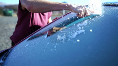 Foto de Close-Up Hand Clearing Frost para el viaje por carretera de invierno Viaje por la mañana. Preparación de parabrisas de coche con rascador de hielo - Imagen libre de derechos