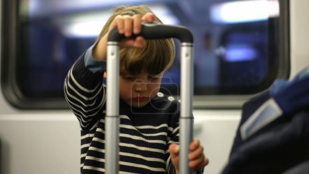 Photo for Little boy passenger playing with suitcase top handle. solo play of child passing the time while traveling by train - Royalty Free Image