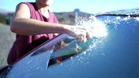 Foto de Close-Up Hand Clearing Frost para el viaje por carretera de invierno Viaje por la mañana. Preparación de parabrisas de coche con rascador de hielo - Imagen libre de derechos