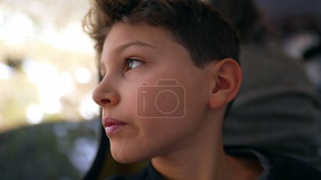 Photo for Thoughtful young boy during train trip looking at landscape scenery pass by, close-up face of pre-teen child in contemplative gaze - Royalty Free Image