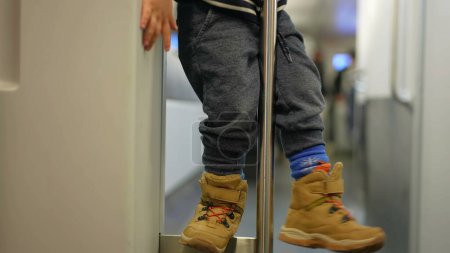 Téléchargez les photos : Petit garçon ennuyé dans le train tenant Metal Bar, enfant jouant seul dans le train au milieu de l'ennui dans les transports en commun - en image libre de droit
