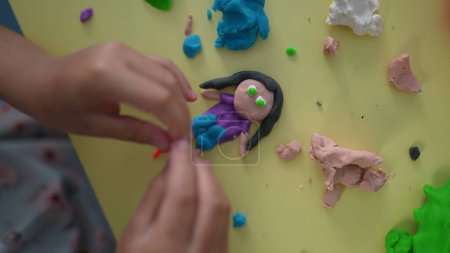 Téléchargez les photos : Moules pour enfants Formes imaginées de Play Clay, mains d'enfant en gros plan créant des figures de bâton avec de l'argile vue d'en haut, créativité imaginative - en image libre de droit