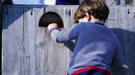 Téléchargez les photos : Petit garçon escalade prudemment échelle en bois sur la structure du terrain de jeu - en image libre de droit