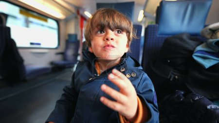Téléchargez les photos : Garçon caucasien assis dans le train savourant un biscuit au beurre, se livrant à une gâterie de biscuits pendant son voyage - en image libre de droit