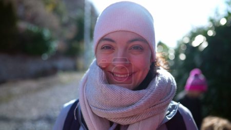 Foto de Retrato de una mujer feliz usando bufanda y gorro durante la estación fría, cara de cerca de una persona femenina caucásica de 30 años sonriendo - Imagen libre de derechos