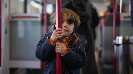 Photo for Child holding into train metal vertical bar turning in circles to pass the time while traveling commute - Royalty Free Image