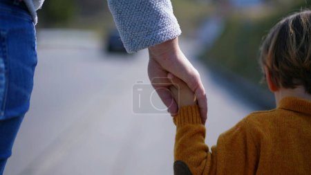 Photo for A mother and her child, united by hands, journey together outside. This simple yet meaningful act showcases the timeless bond of familial love - Royalty Free Image