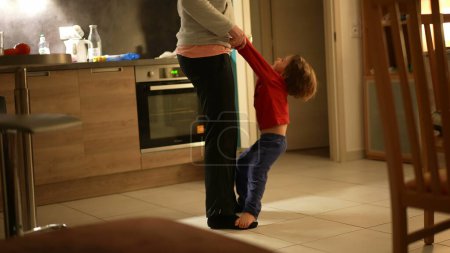 Téléchargez les photos : Orteils et tonalités - Mère et fils sincères dansant dans la cuisine-salon - en image libre de droit