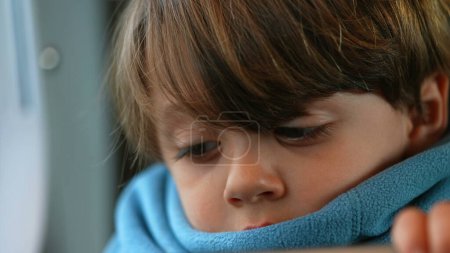Foto de Primer plano de un niño contemplativo caucásico, encerrado en una bufanda, reflejando una profundidad de introspección, encapsulando un profundo estado meditativo - Imagen libre de derechos