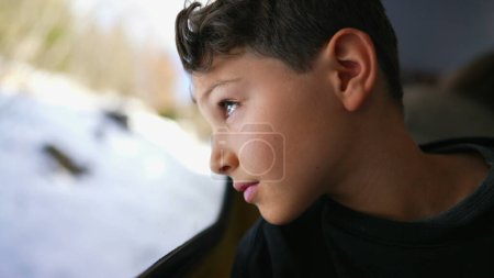 Téléchargez les photos : Voyage en train Contemplation du regard réfléchi de l'enfant sur le paysage tout en s'appuyant sur la fenêtre du train en regardant la vue avec une expression réfléchie et coûteuse - en image libre de droit