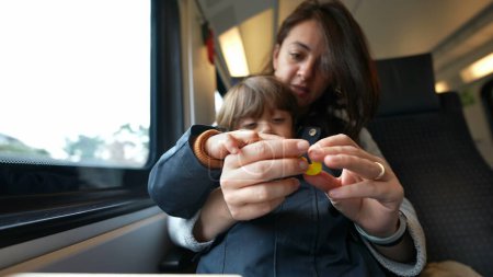 Photo for Focused mother guiding her son in counting during a train journey, embodying the essence of homeschooling and childhood learning on-the-go - Royalty Free Image