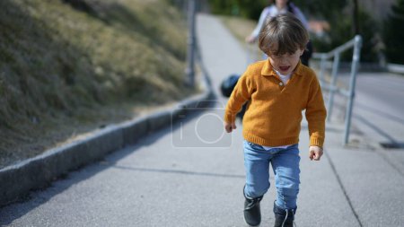 Photo for Close-up of elated boy in yellow pullover sprinting in autumn?Cheerful child's face captured mid-run on a fall day - Royalty Free Image