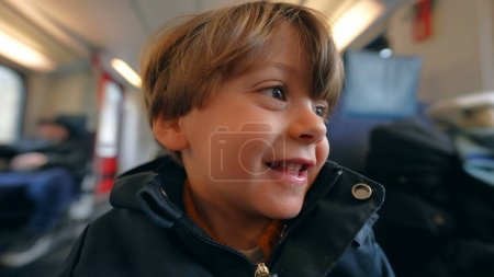 Foto de Feliz cara de niño sentado en el tren. Chico alegre viajando en tren de alta velocidad. primer plano cara de sonrisa - Imagen libre de derechos