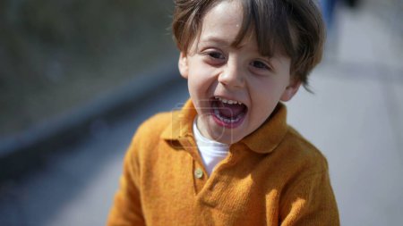 Photo for Close-up of elated boy in yellow pullover sprinting in autumn?Cheerful child's face captured mid-run on a fall day - Royalty Free Image