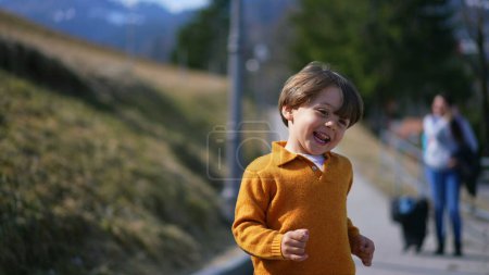 Photo for Joyful excited little boy running outside during autumn day wearing yellow pullover. Close-up face of child in motion sprinting forward feeling carefree - Royalty Free Image