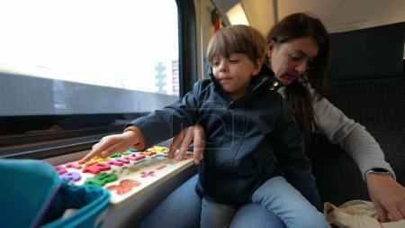 Téléchargez les photos : Mère engagée conduisant une session d'apprentissage avec son enfant à bord d'un train à grande vitesse, illustrant l'éducation mobile de l'enfance - en image libre de droit