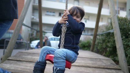 Photo for Happy Child Sliding Down Rope at Autumn Playground. Joyful Kid Holding Onto Rope and Enjoying Slide in Fall Park - Royalty Free Image