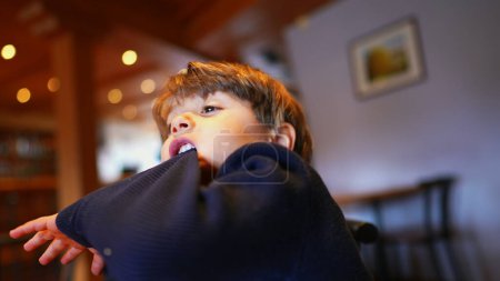 Téléchargez les photos : Morsures d'ennui, Petit garçon tirant la manche avec les dents, ralenti au restaurant - en image libre de droit