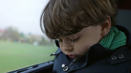 Téléchargez les photos : Enfant ennuyé voyageant en train, gros plan sur le visage de l'enfant qui s'ennuie pendant qu'il fait la navette ou voyage - en image libre de droit