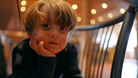 Photo for Hungry Anticipation of Cheerful Boy Sitting with hand in chin, Patiently Awaiting Meal in Restaurant - Royalty Free Image