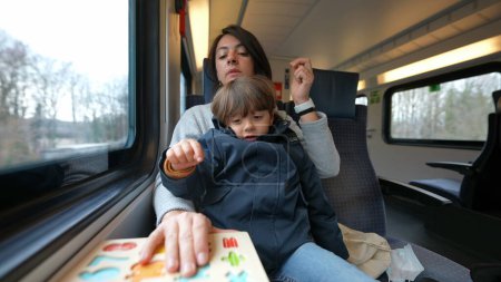 Foto de Madre sosteniendo a su hijo mientras viaja en tren en viaje diario, padres multi-tarea sobre la marcha - Imagen libre de derechos